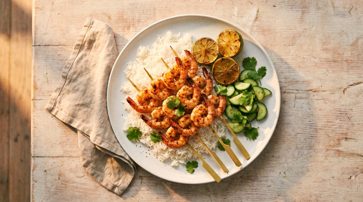 Barbecued prawn skewers seasoned with Chooki's Chilli Chicken Salt on coconut rice with charred lime halves, cucumber and coriander