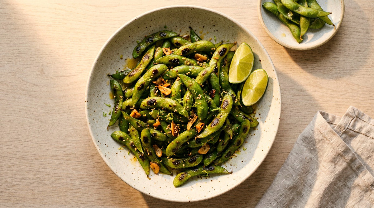 Blistered charred edamame pods with crispy garlic, sesame seeds and lime wedges, seasoned with Chooki's Original Chicken Salt