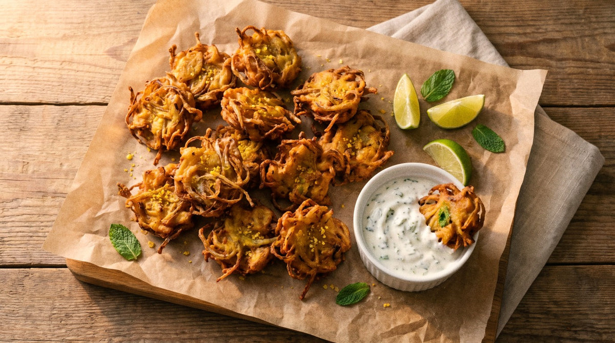 Crispy golden onion bhaji bites seasoned with Chooki's Vinegar Chicken Salt beside a bowl of minty coconut yoghurt and lime wedges